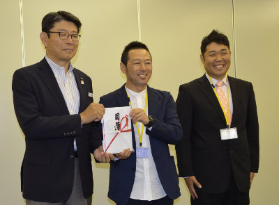 九州電力の新開宮崎支社長から助成目録を受ける延岡男星保育士団の國友団長 中央 右端は川野幸伸事務局長