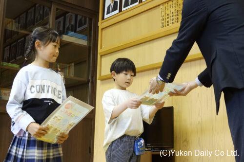 藤本会長（右）から防犯グッズを受け取った甲斐さん（中央）と佐藤さん