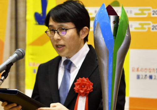 採用された炬火トーチと受賞のあいさつを述べる清山さん